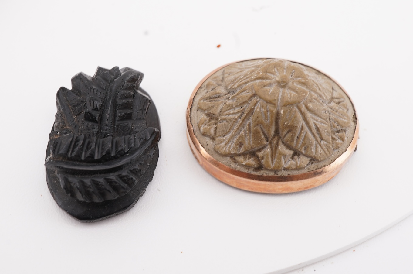 A collection of carved lava fragments, 19th century, once forming a bangle, the fragments variously carved with abstract floral motifs, lion's heads, and a theatrical mask, largest 6.2cm, Condition: fragmentary, but carv